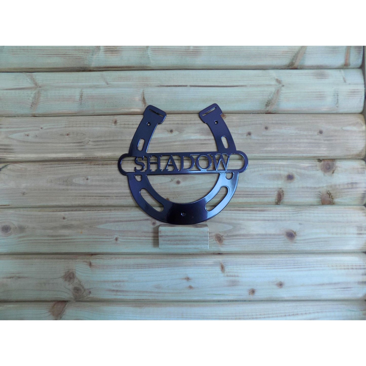black horse shoe personlised name shadow on wooden background
