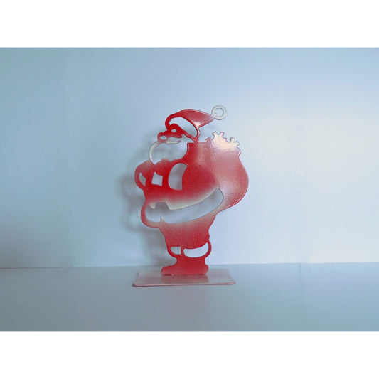 Handcrafted metal Santa ornament in glossy red with white frosted details, holding a sack, White background, Christmas decoration.