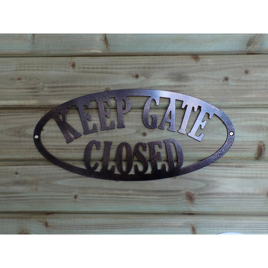 Oval metal sign with the text “KEEP GATE CLOSED”, mounted on timber. Shown in two-tone black and bronze finish, handmade in Ireland