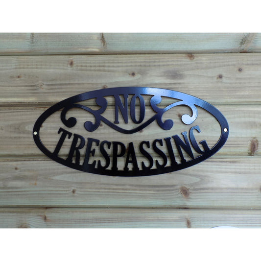 Black powder coated metal no trespassing sign for farm or private property, mounted on a wooden background