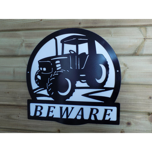Black powder-coated metal farm safety sign featuring a tractor and the word “BEWARE”, mounted on a wooden background